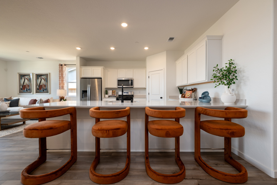 A kitchen with a bar stools.
