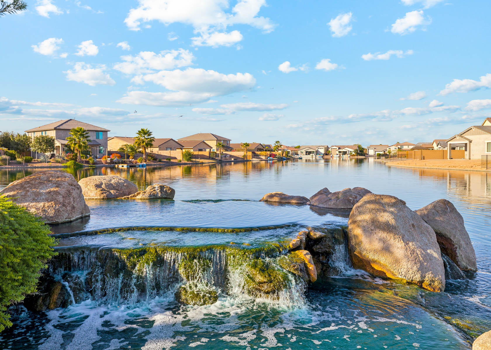 A body of water with rocks and buildings around it.