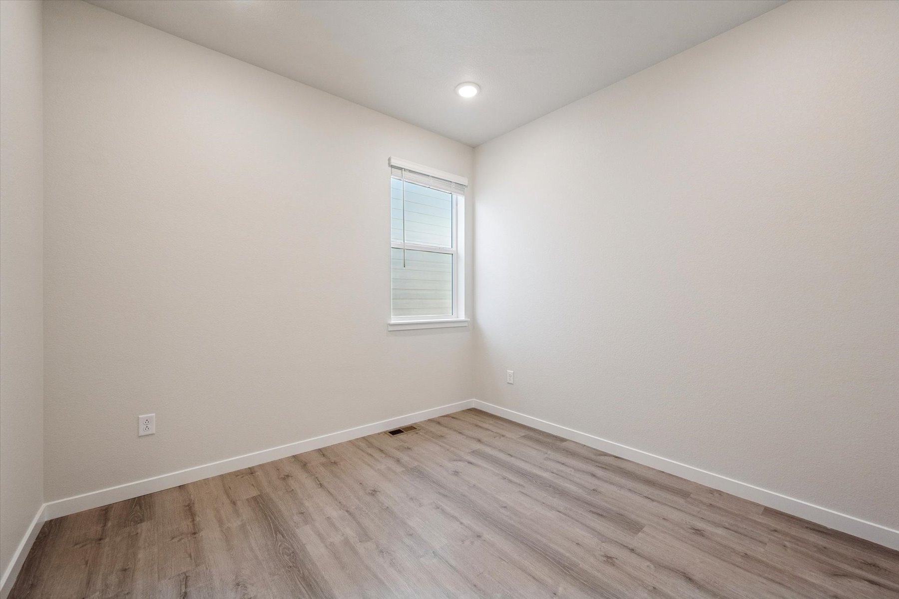 A room with a wood floor and a window.