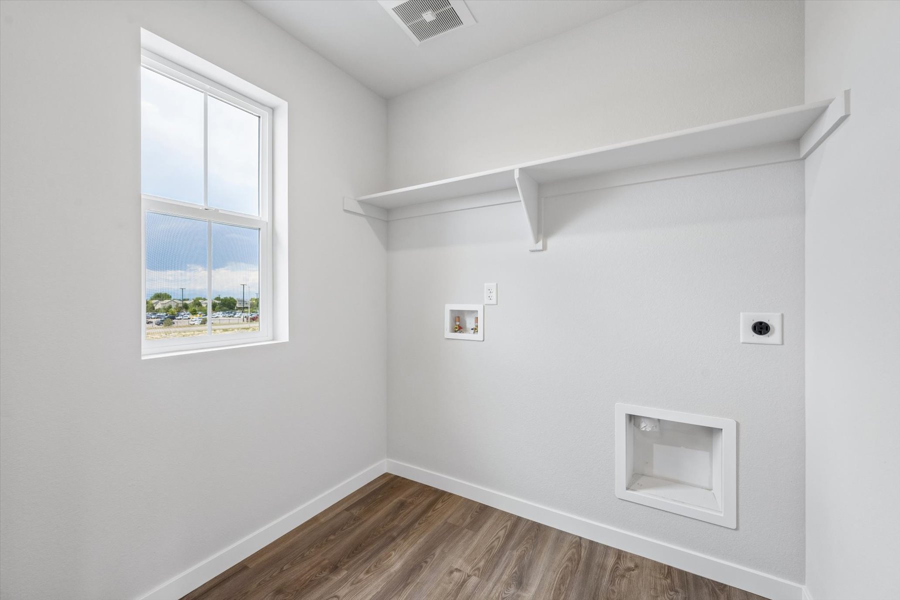 A room with a window and a wood floor.