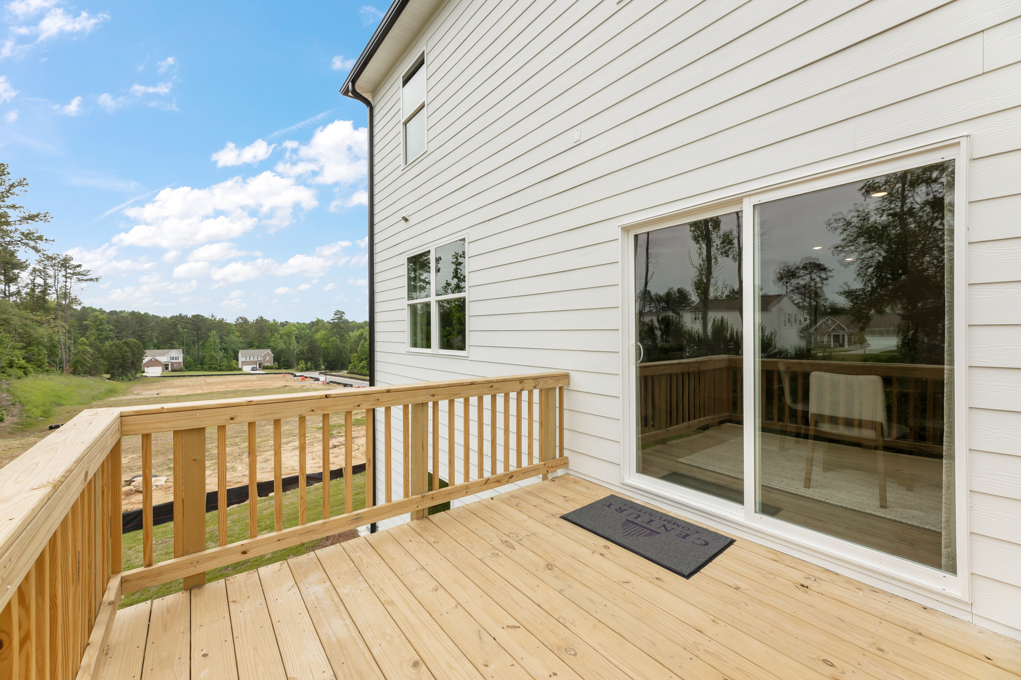 A deck with a view of a field and trees.