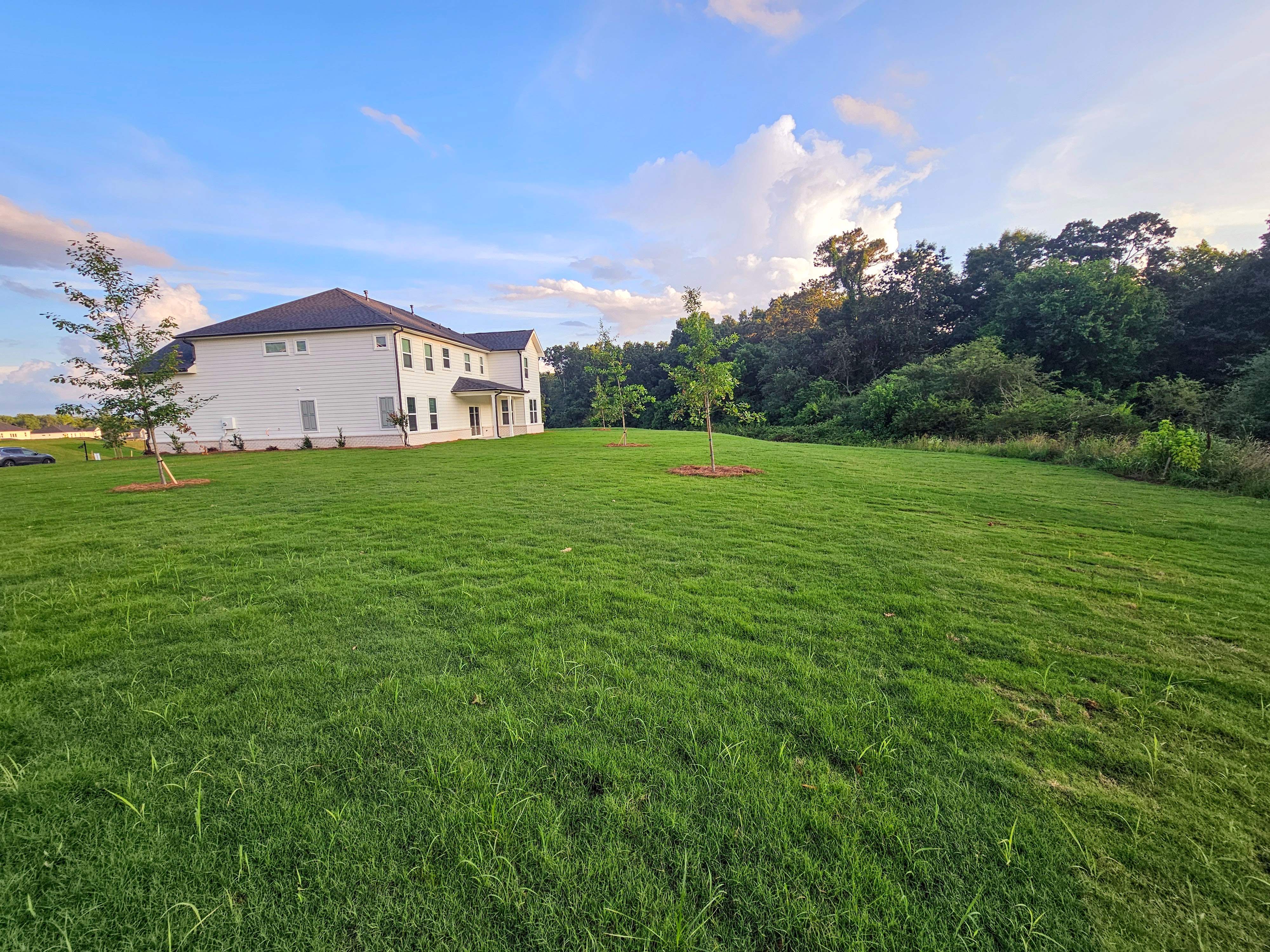 A large green field with a building in the background.