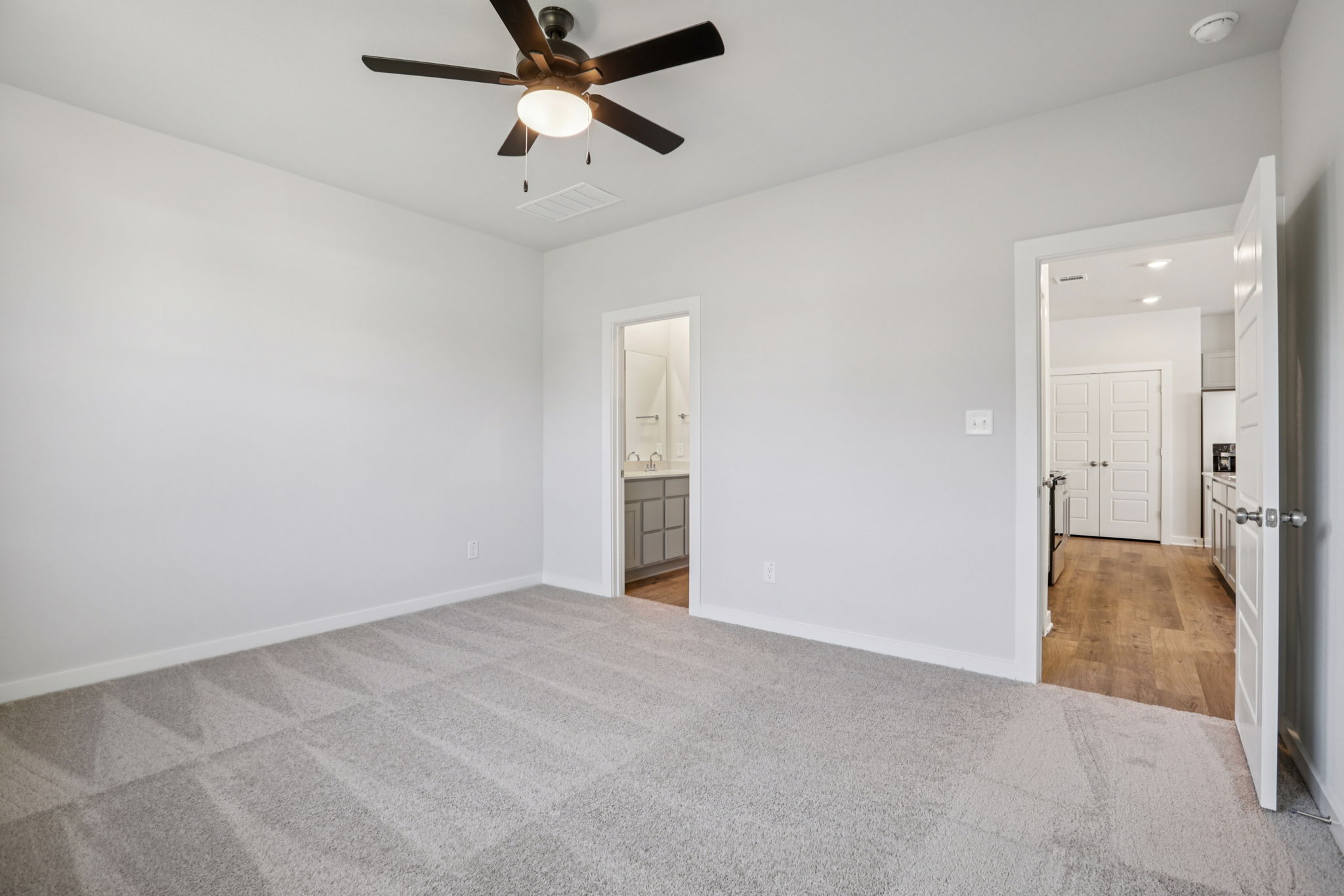 A room with a ceiling fan and a door.