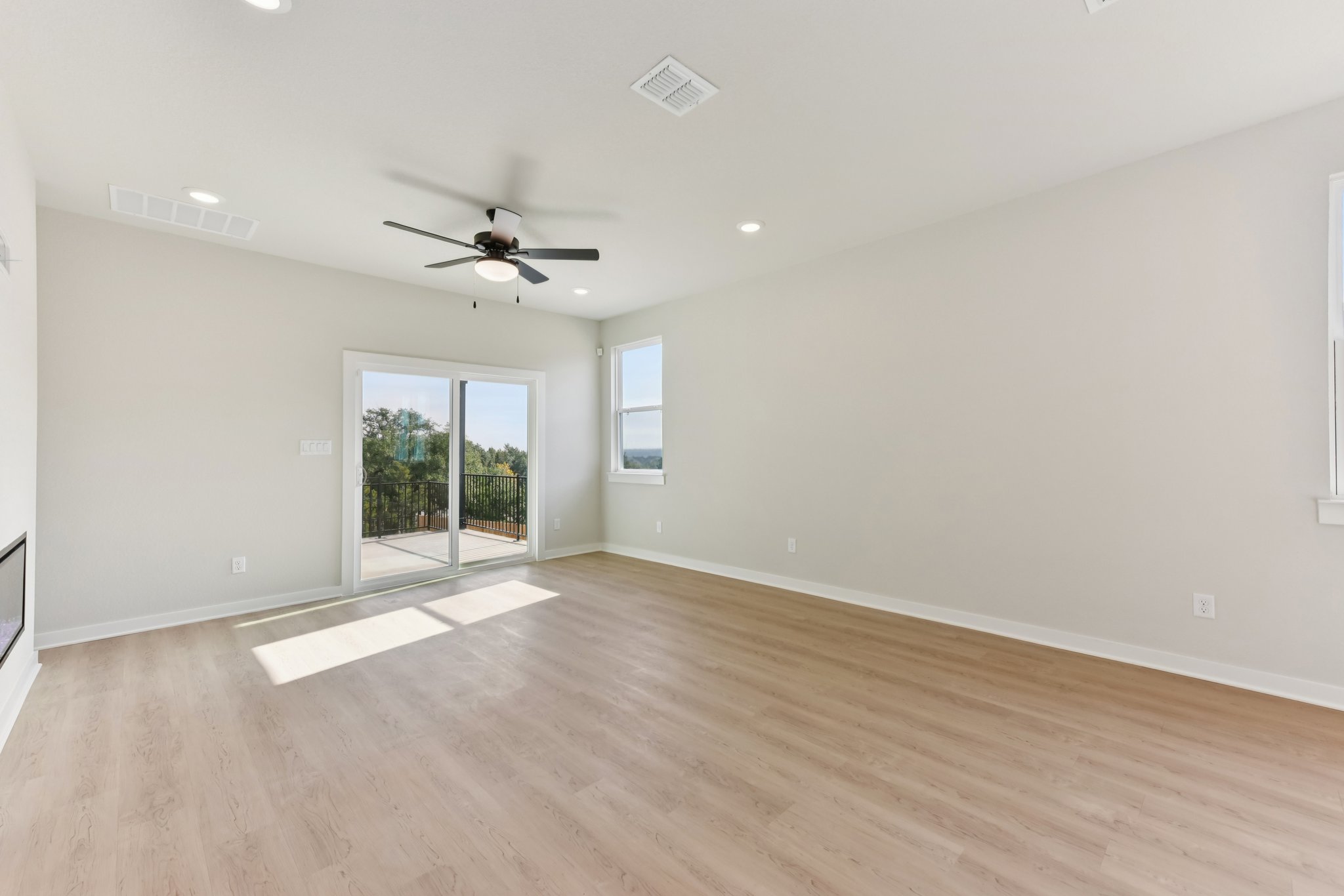 A room with a wood floor and a wood floor with a fan.