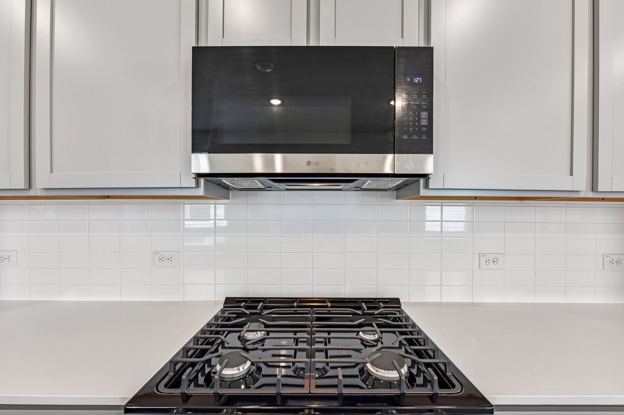 A kitchen with a stove and microwave.
