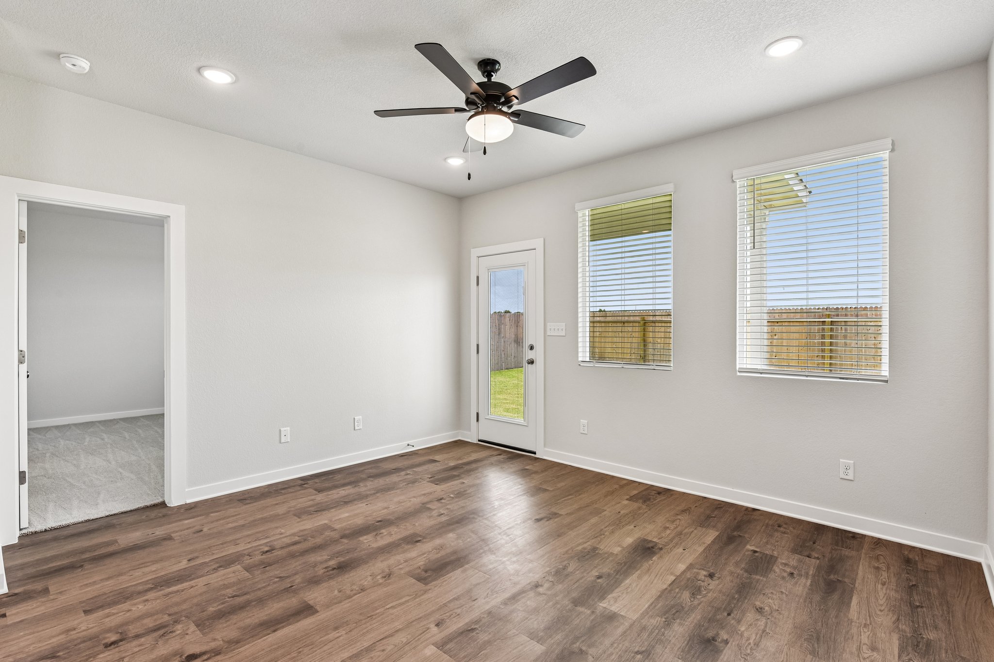 A room with a ceiling fan and a wood floor.