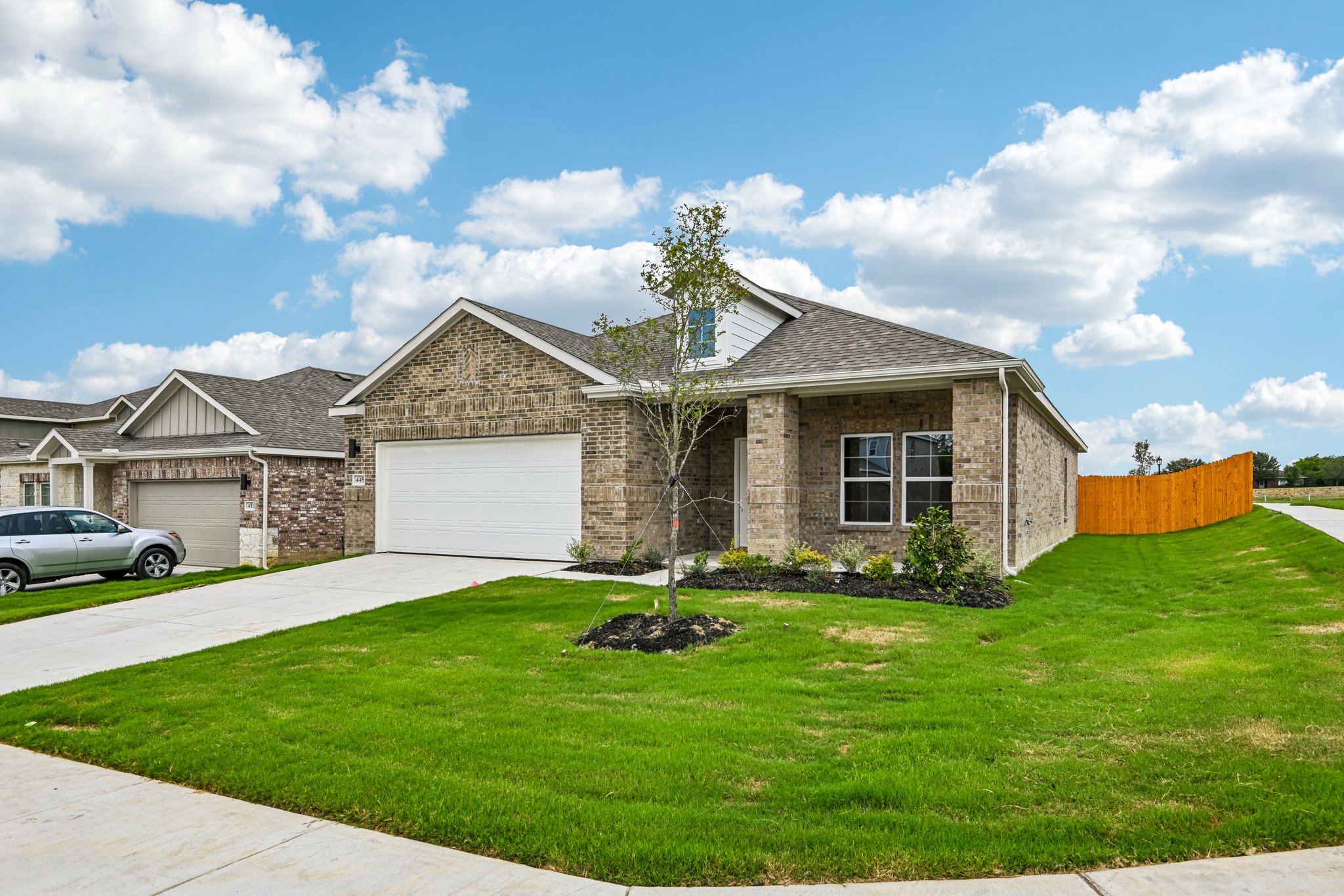 A house with a garage and a car parked in the driveway.
