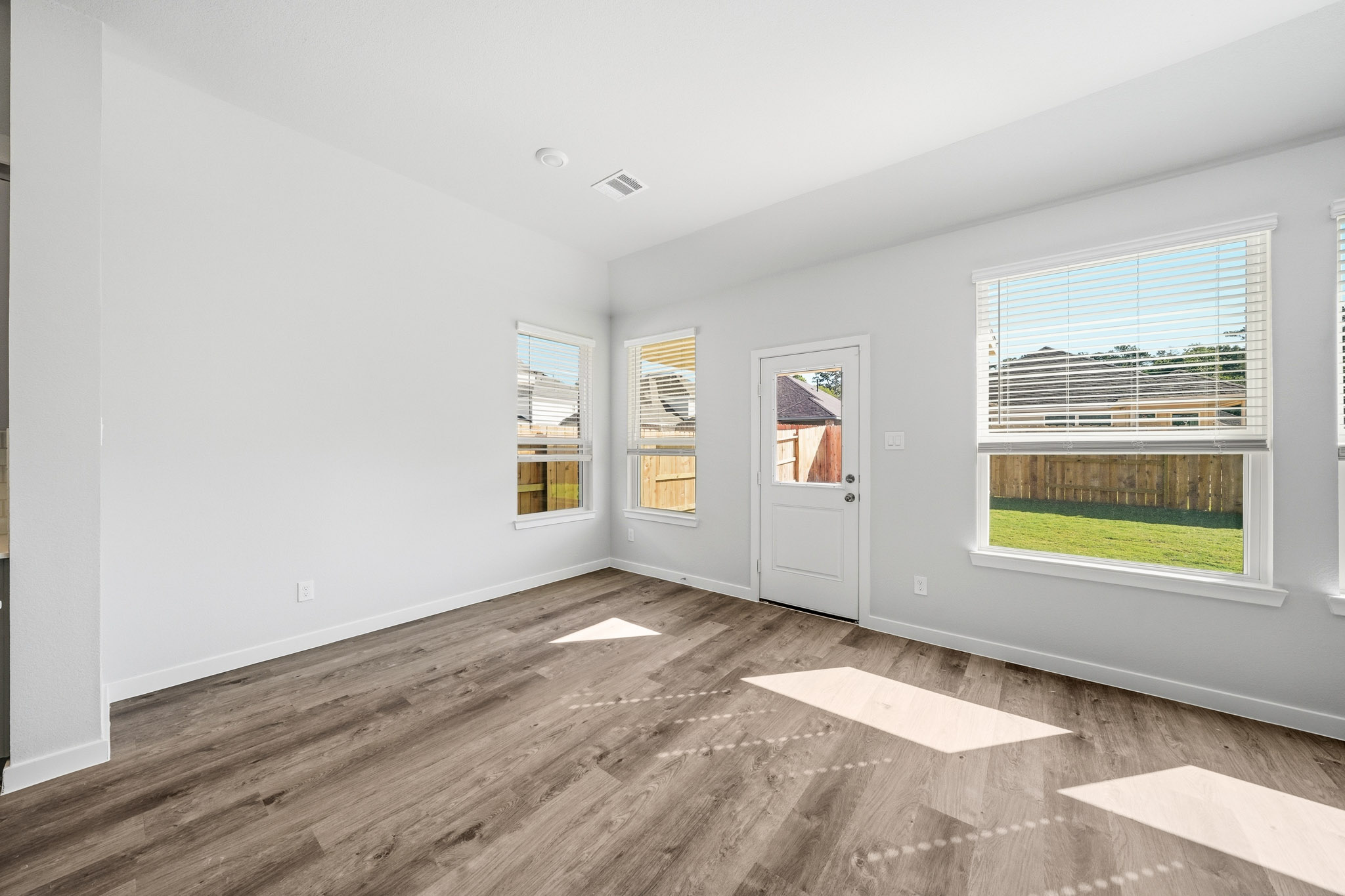 A room with a wood floor and a wood floor with a door and a window with a view.