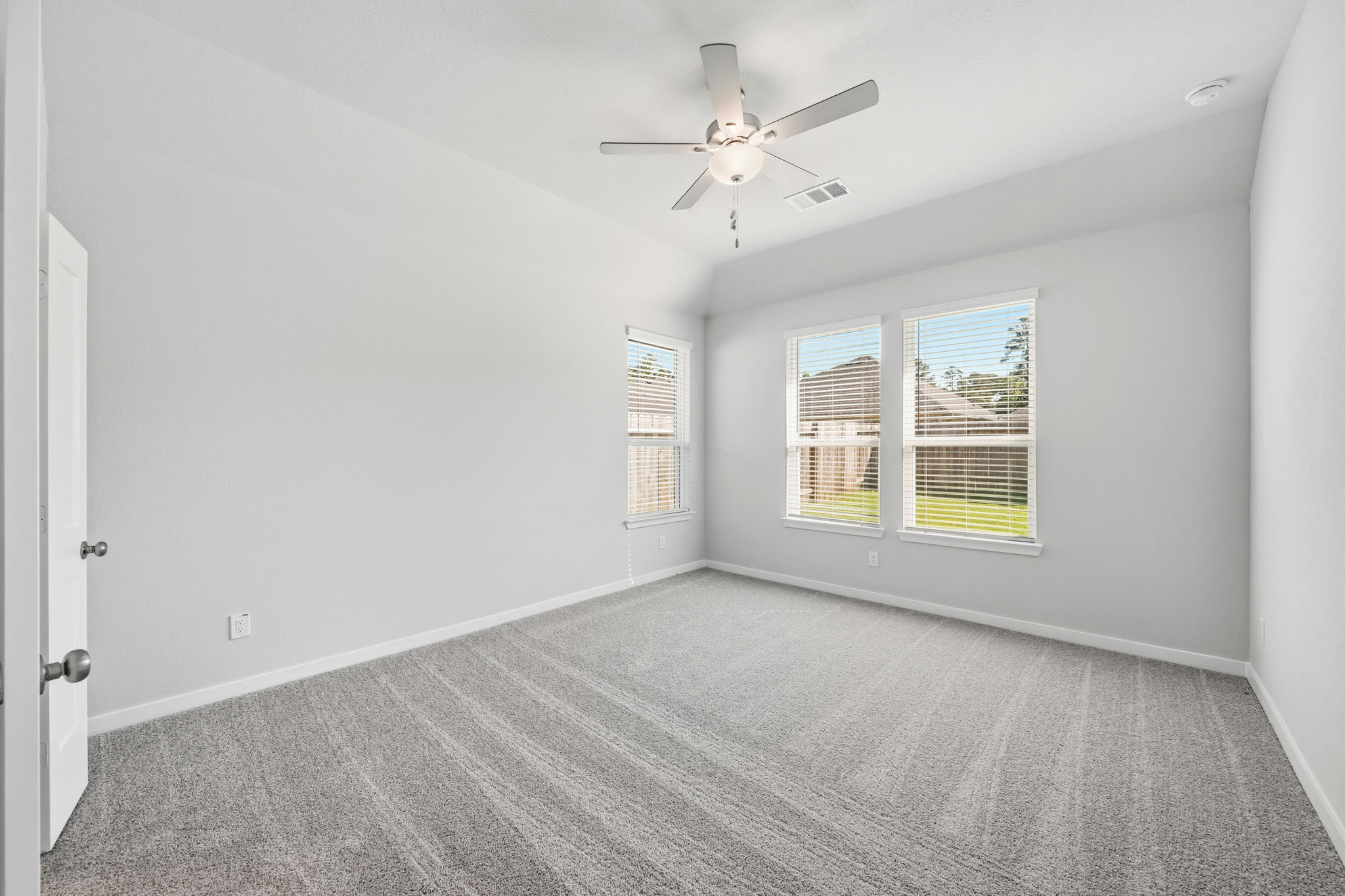 A room with a ceiling fan and windows.