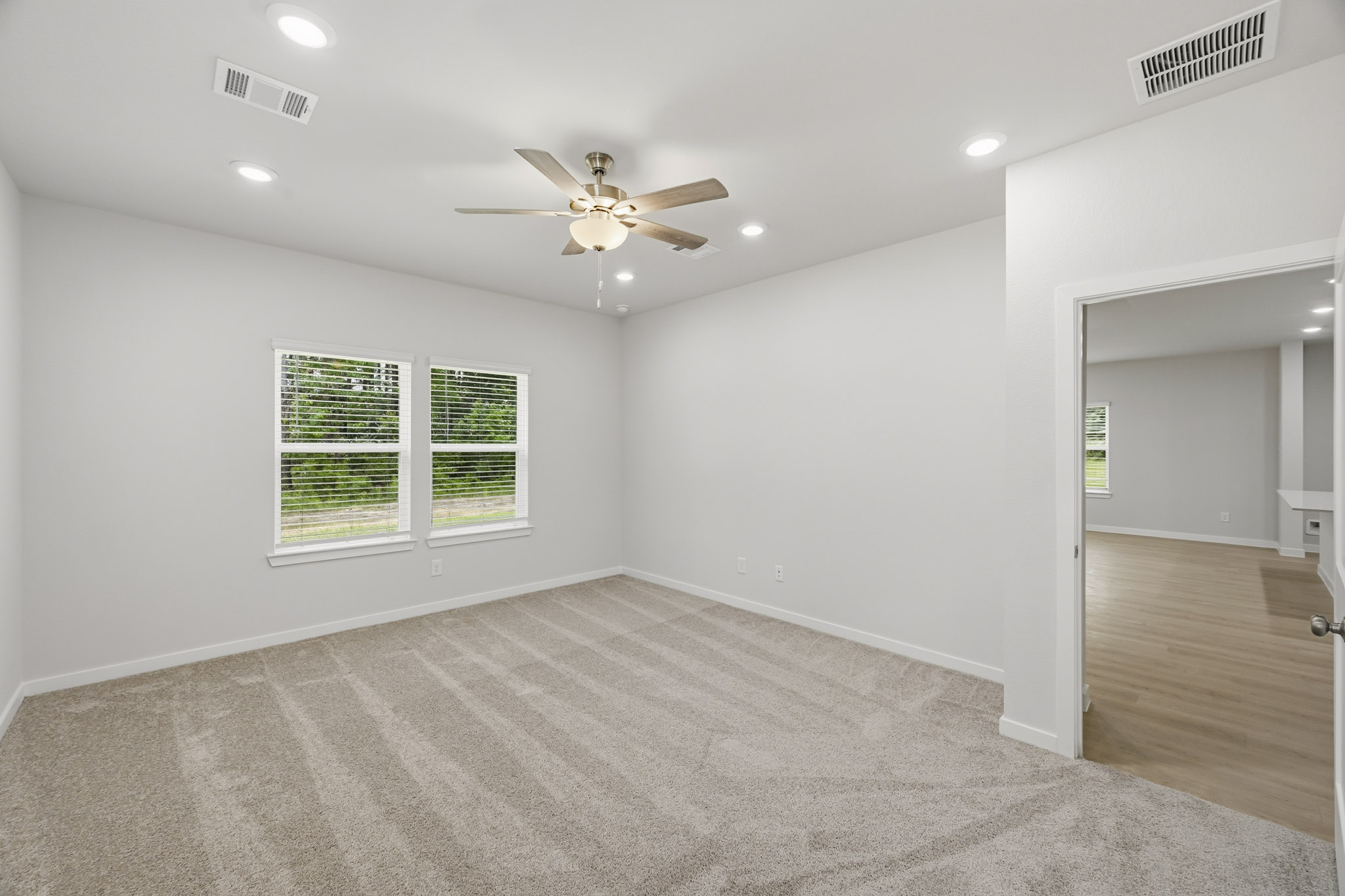 A room with a ceiling fan and a wood floor.