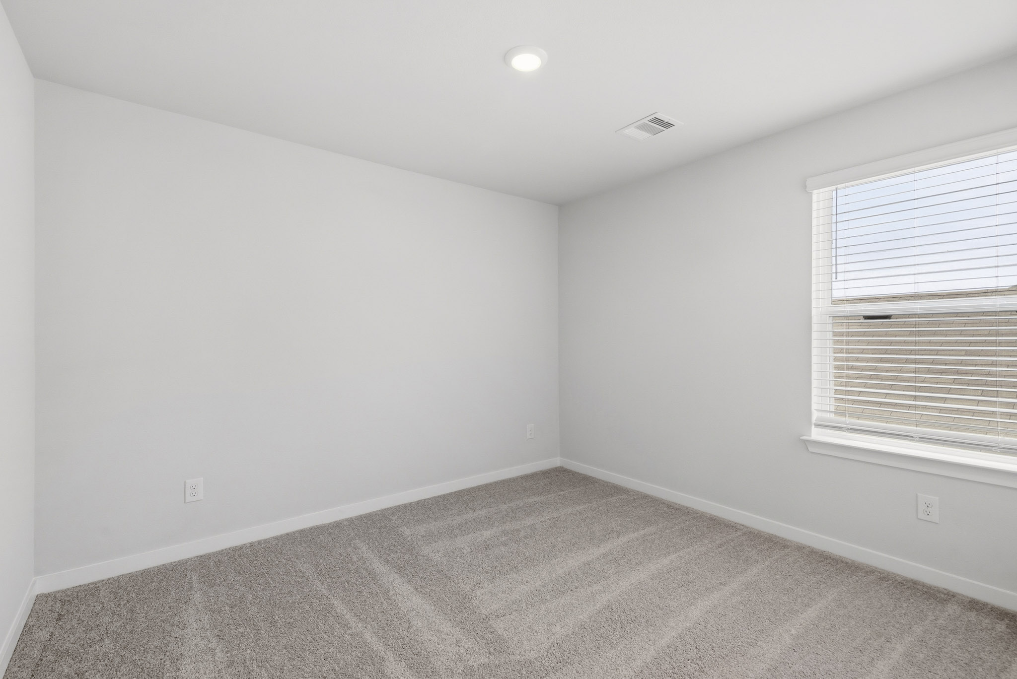 A room with a carpet and a window.