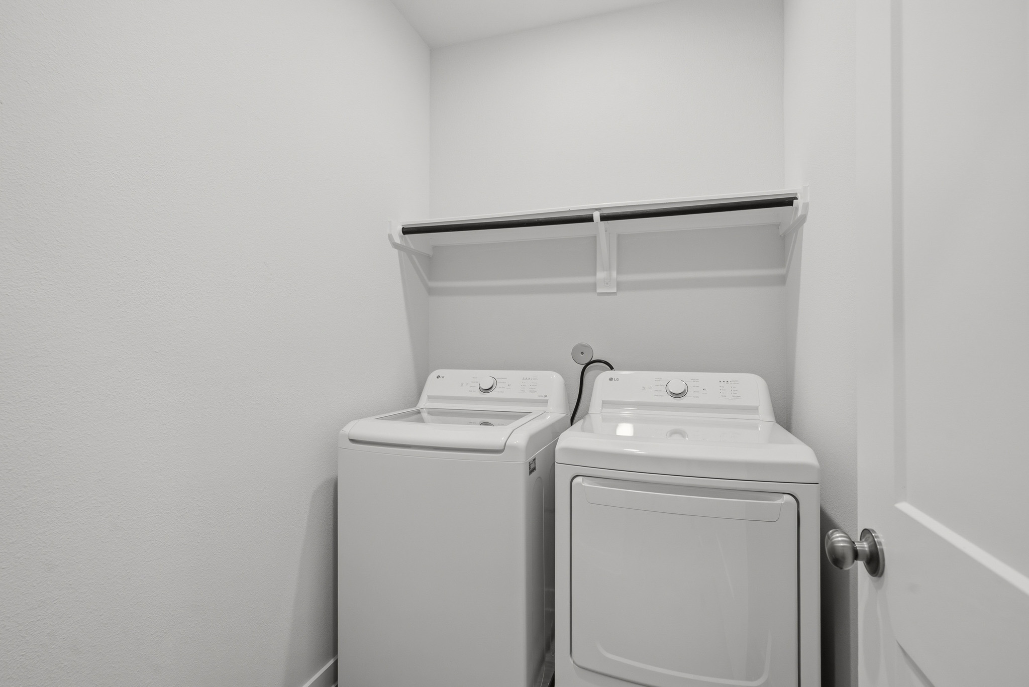 A white washing machine and a white shelf.