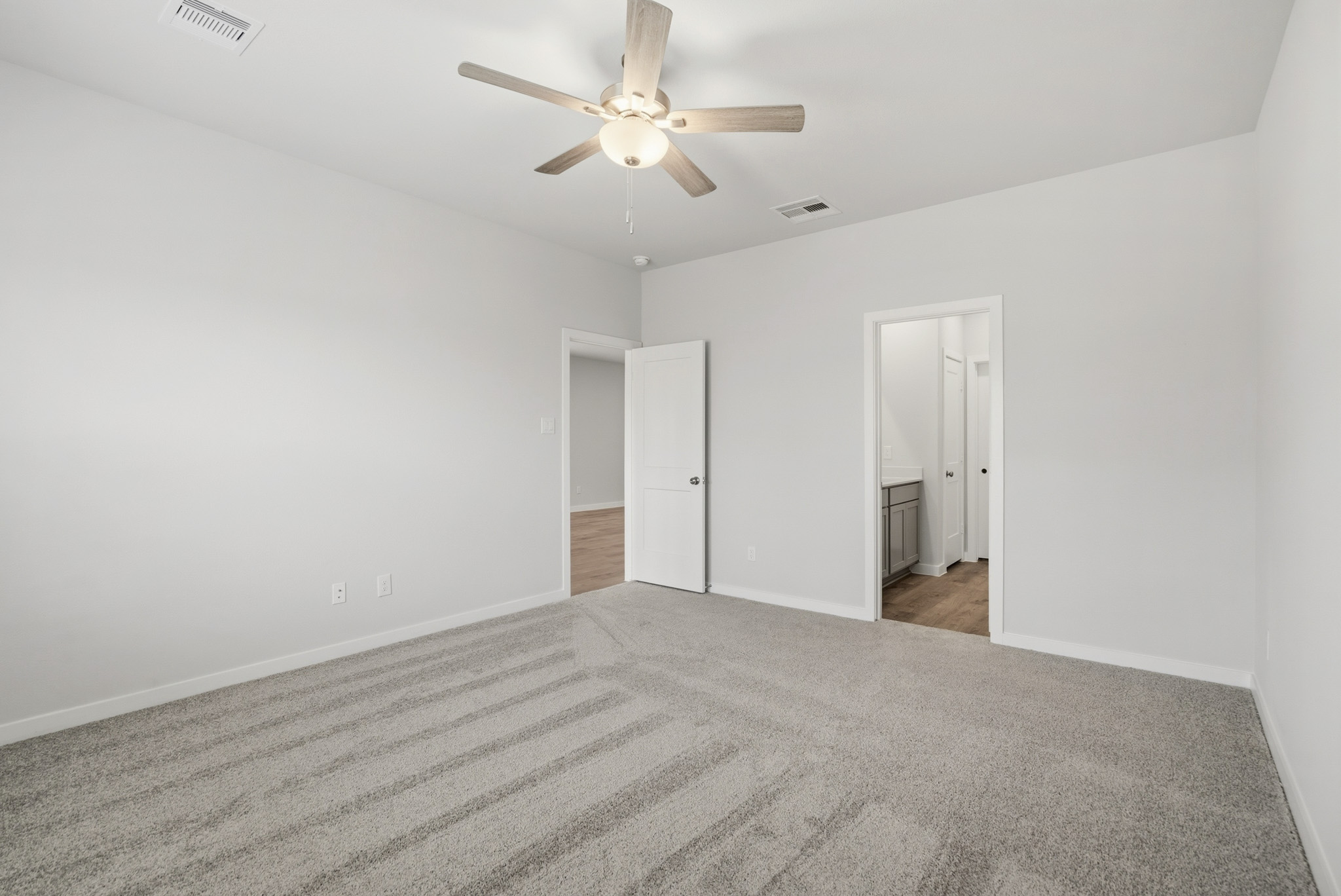 A room with a ceiling fan and a carpet.