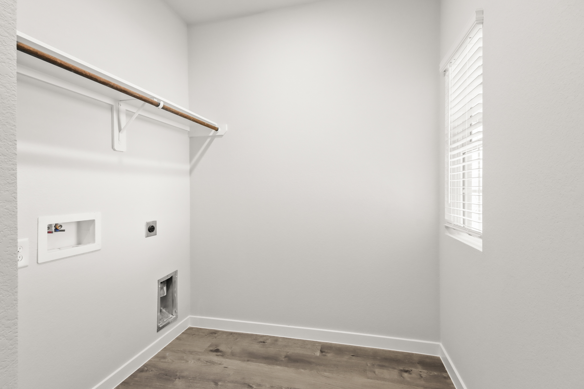 A room with a wood floor and a white wall with a vent.