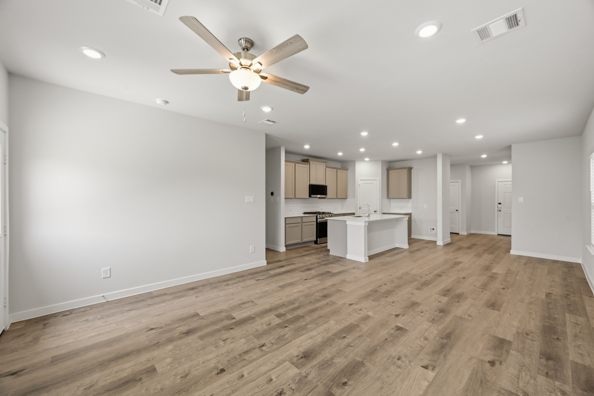 A large empty room with a ceiling fan and a wood floor.
