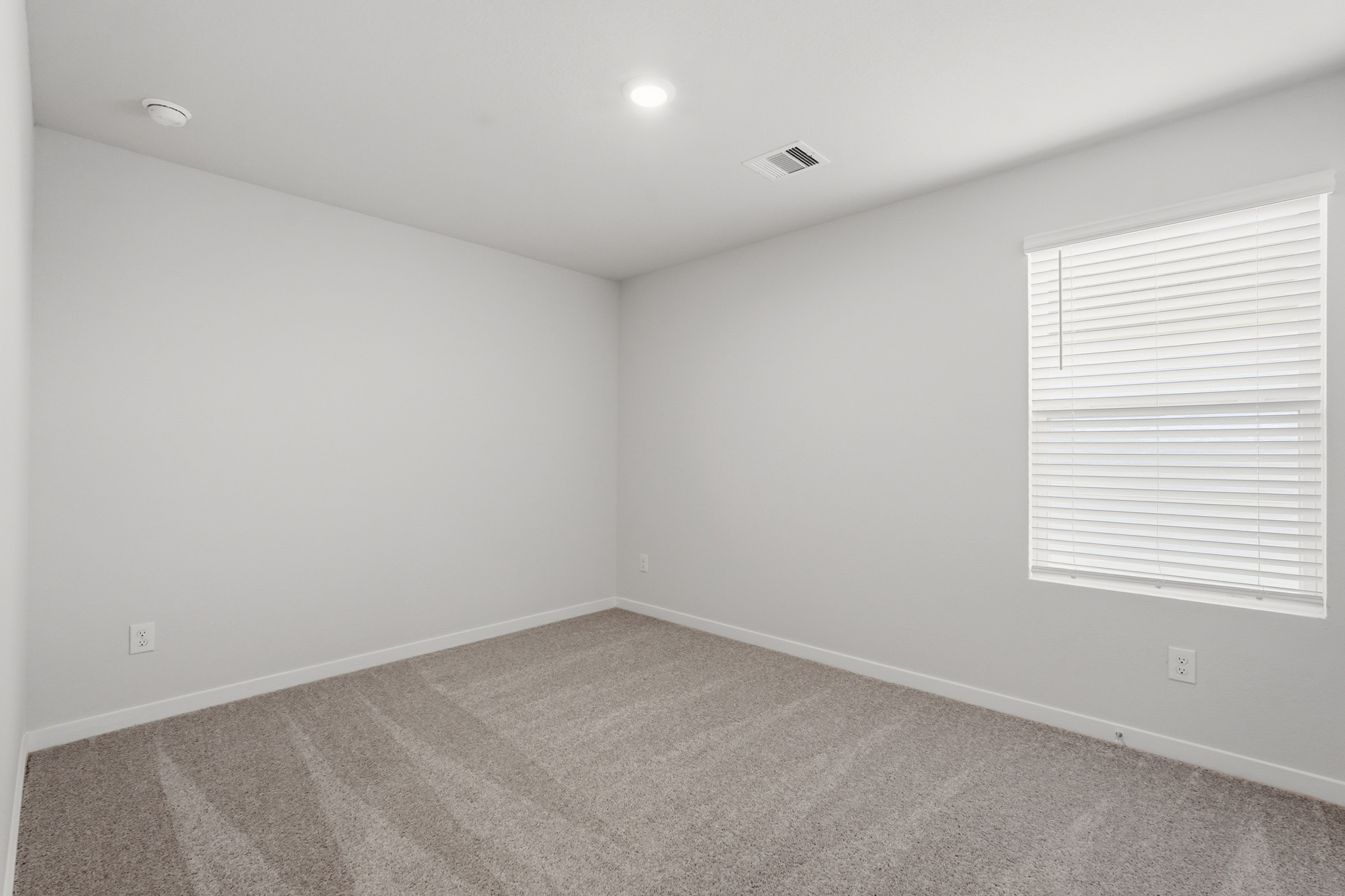 A room with a carpet and a window.