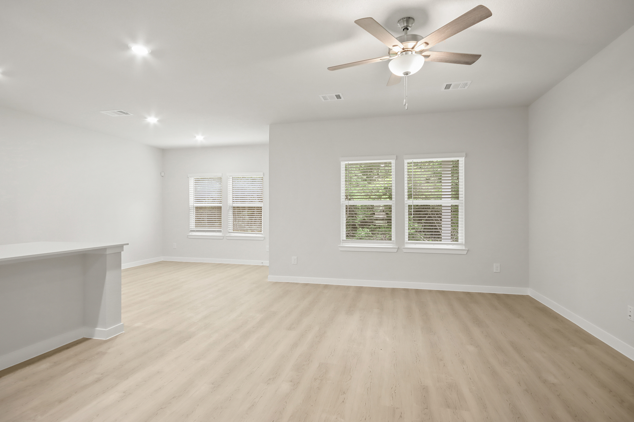 A room with a ceiling fan and a wood floor.