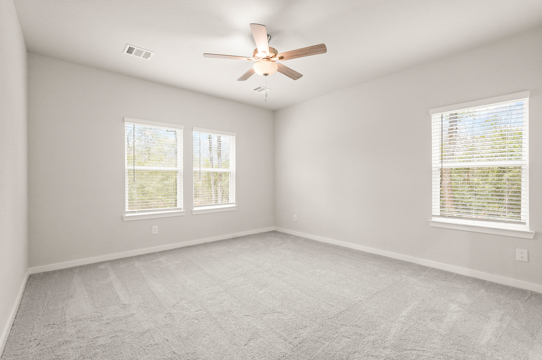 A room with a ceiling fan and windows.