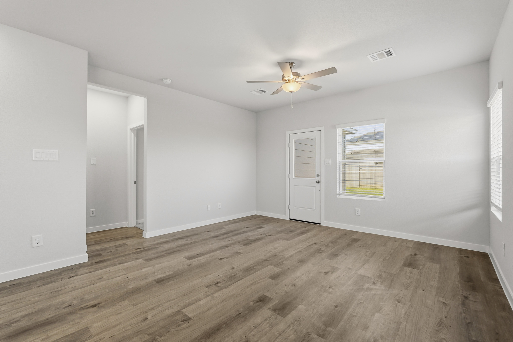 A room with a wood floor and a ceiling fan.