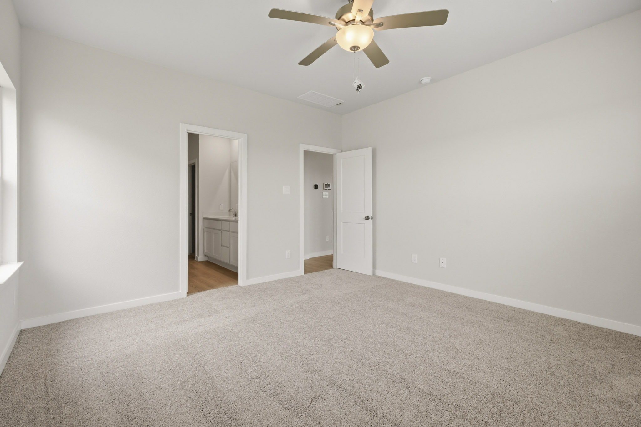 A room with a ceiling fan and a carpet.