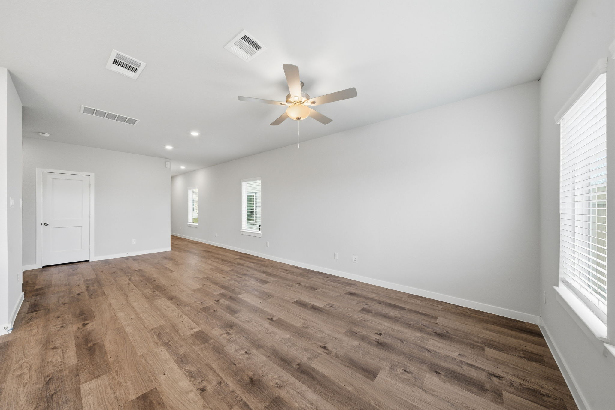 A room with a ceiling fan and wood floor.