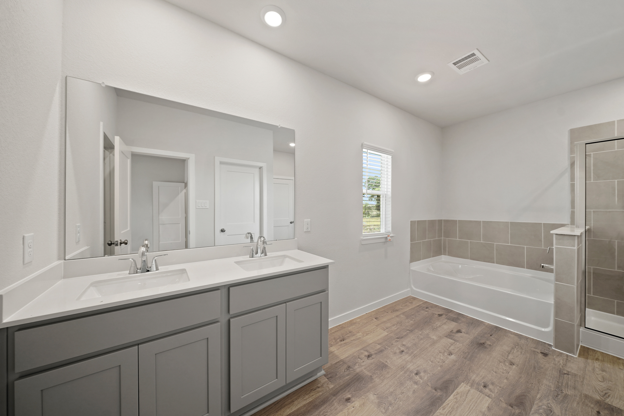 A bathroom with a tub sink and a mirror.