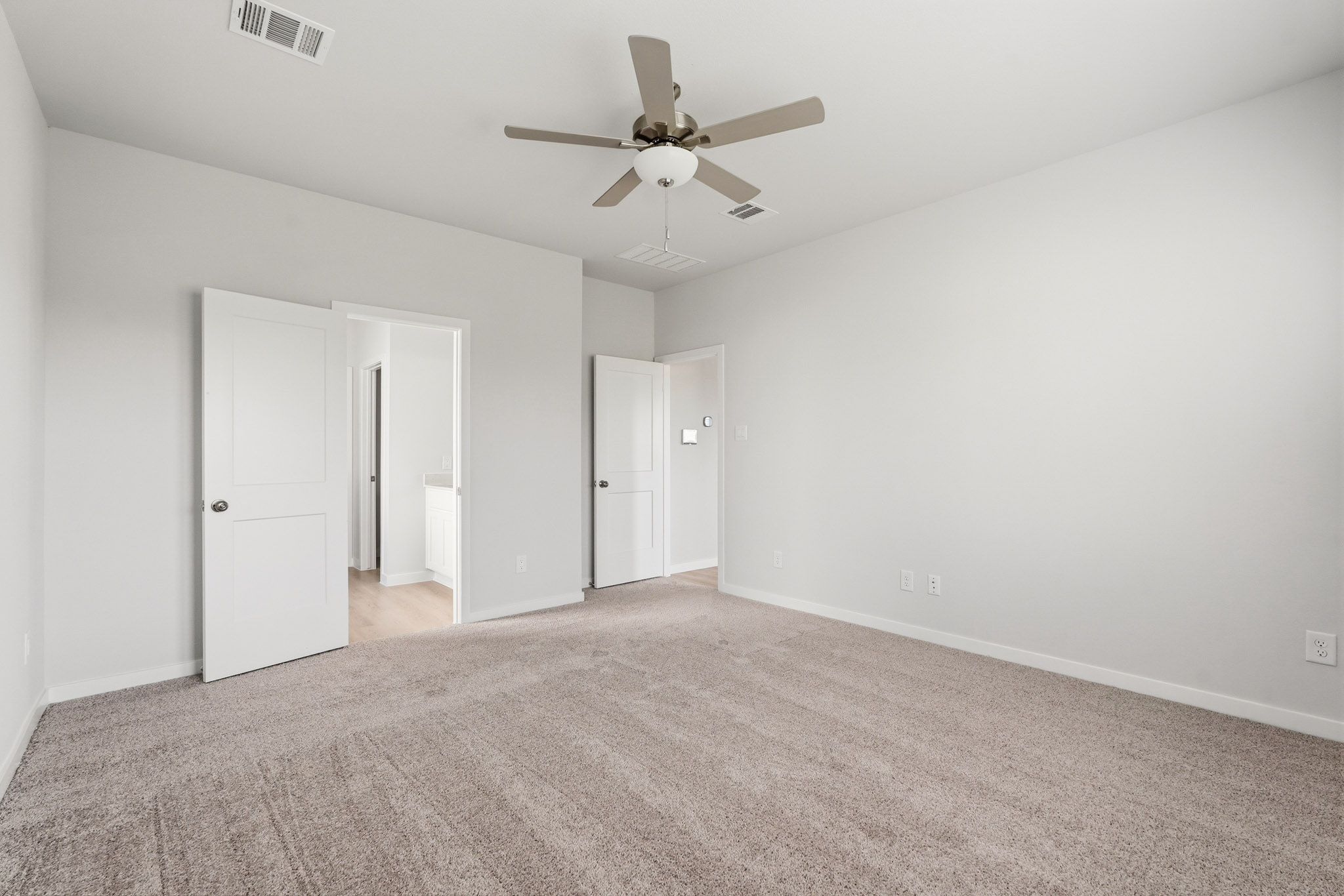 A room with a ceiling fan and white doors.
