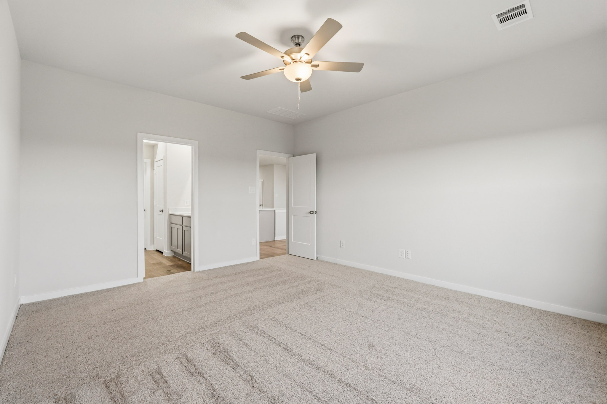 A room with a ceiling fan and a carpet.