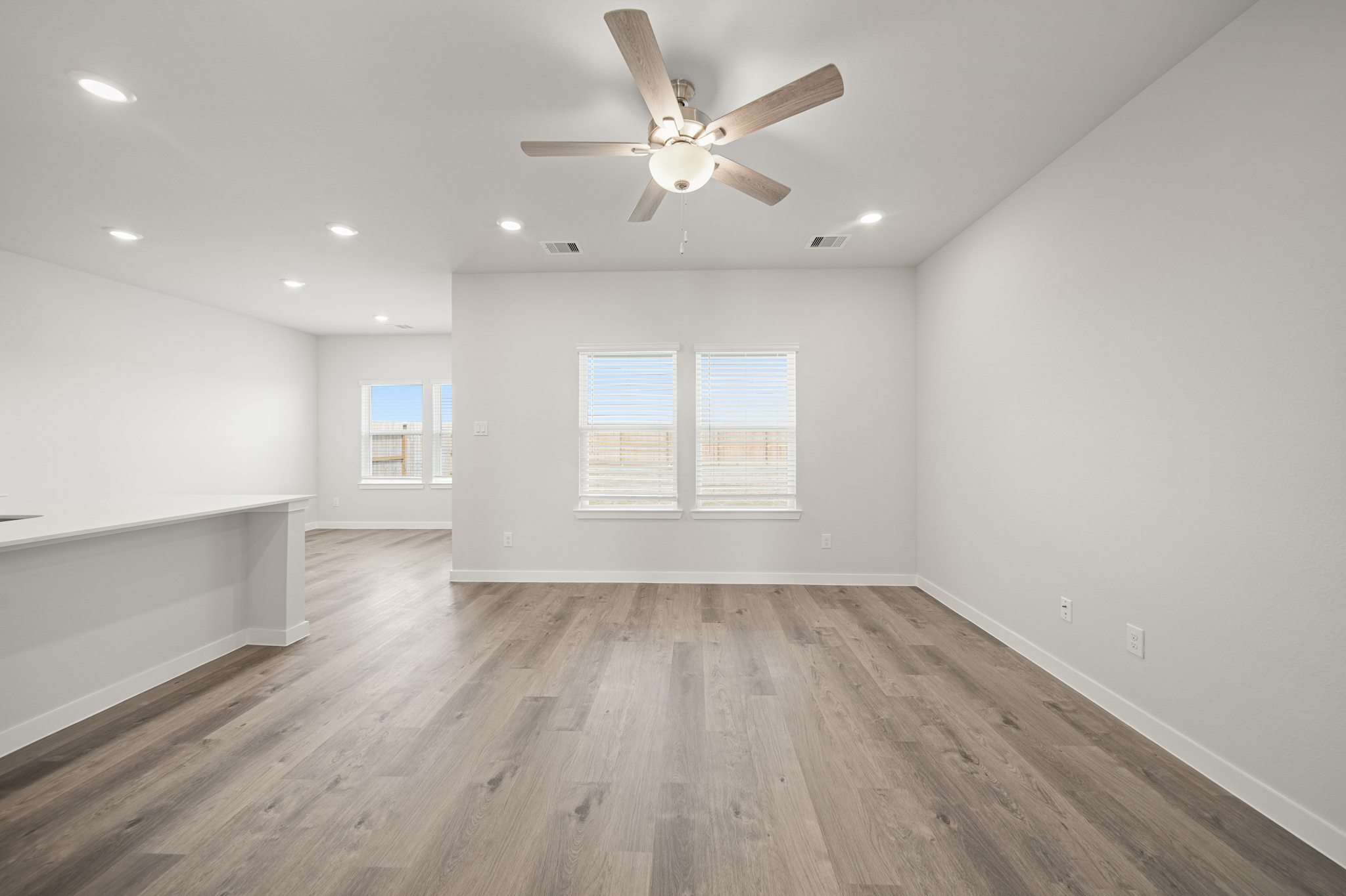 A room with a ceiling fan and a wood floor.