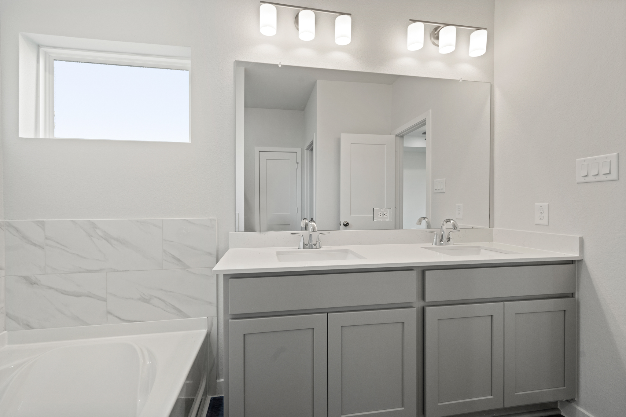 A bathroom with a tub sink and mirror.
