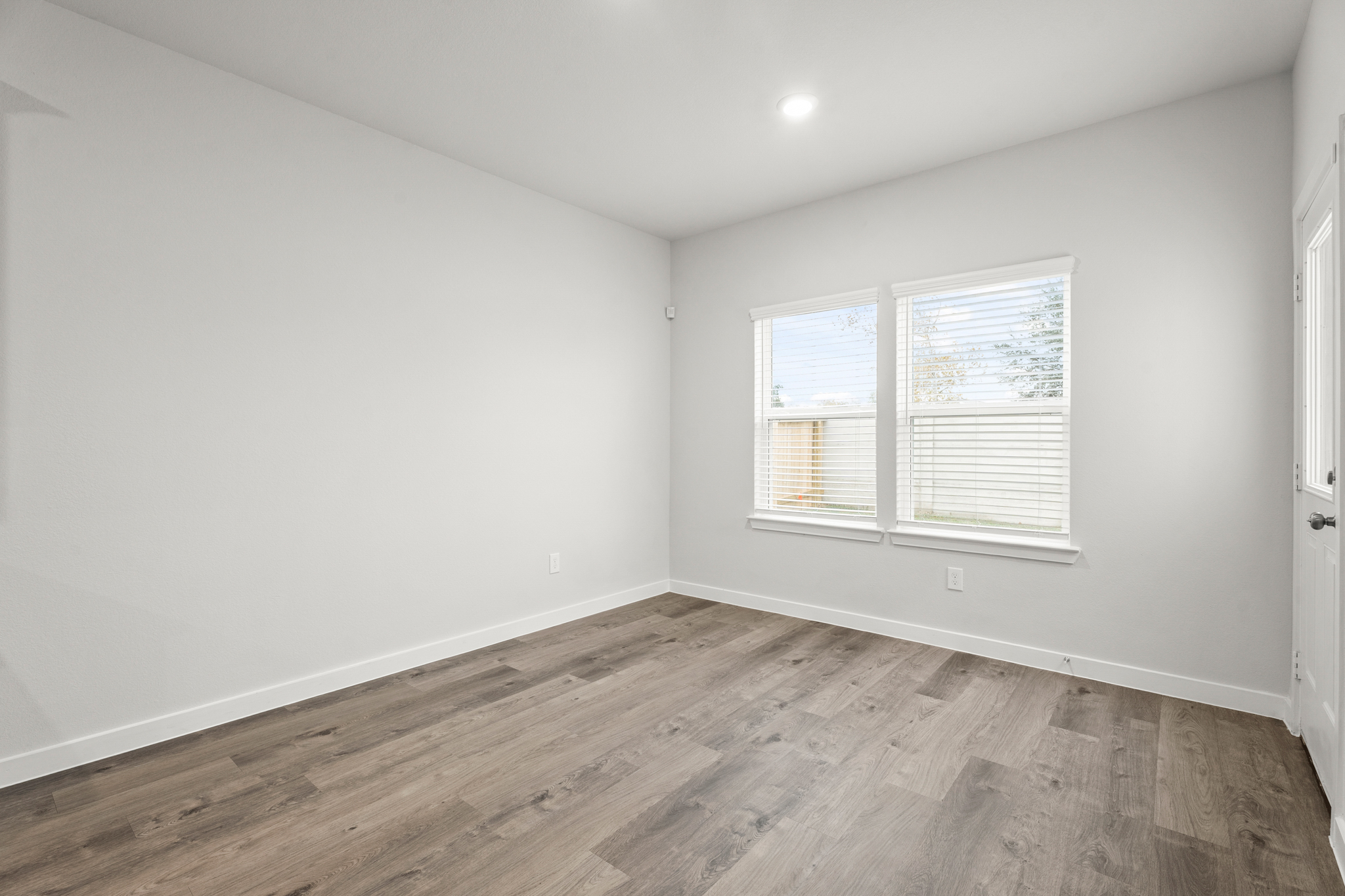 A room with a wood floor and windows.