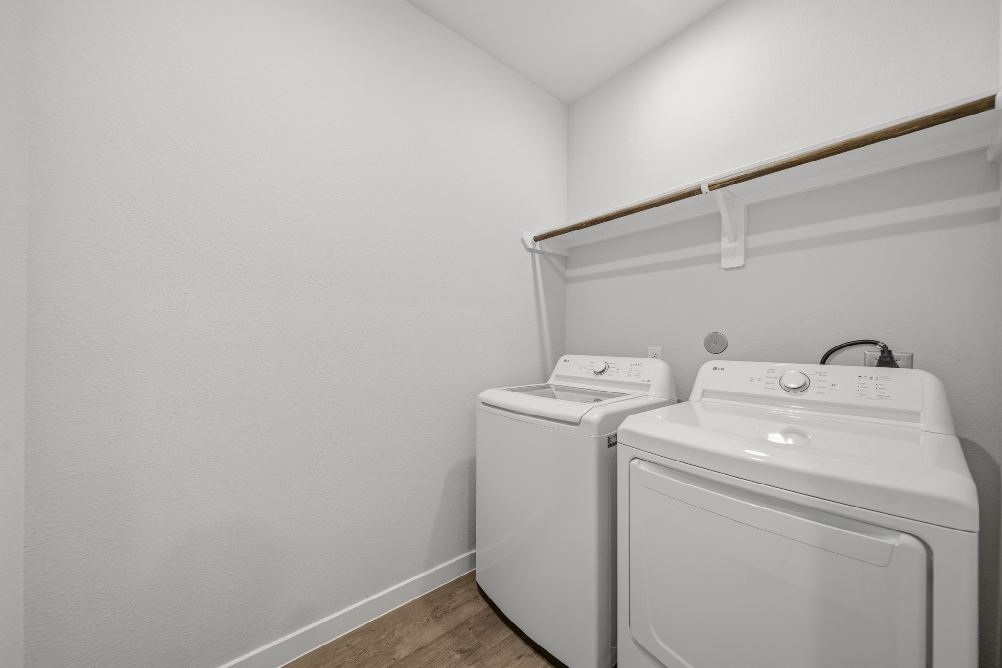 A white laundry room with a white wall and a white laundry machine.