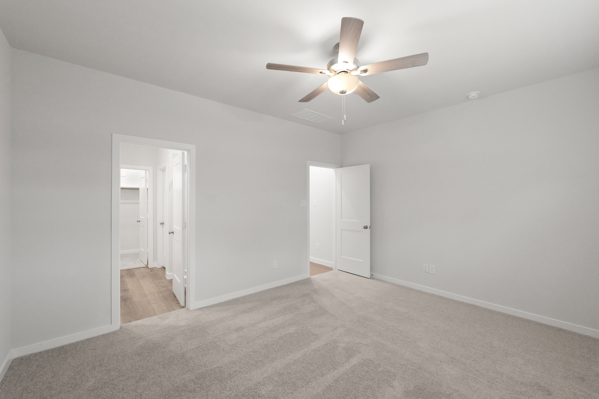 A room with a ceiling fan and white doors.