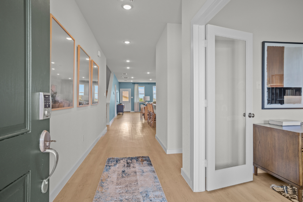 A hallway with a mirror and a rug.