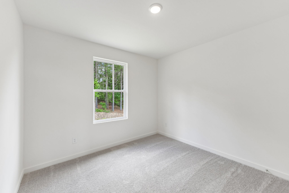 A room with a window and a white wall.